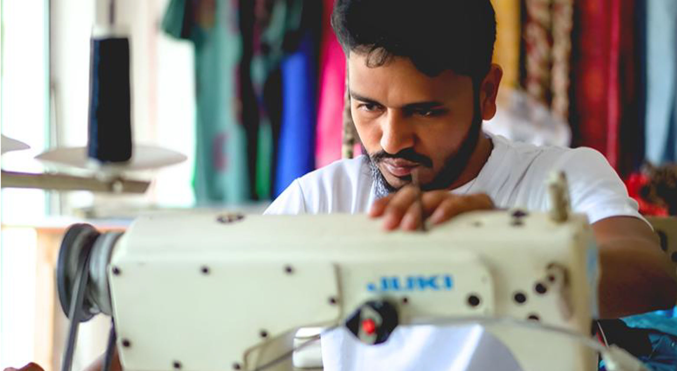 Rabiul Islam Awal working intently on a modern sewing machine
